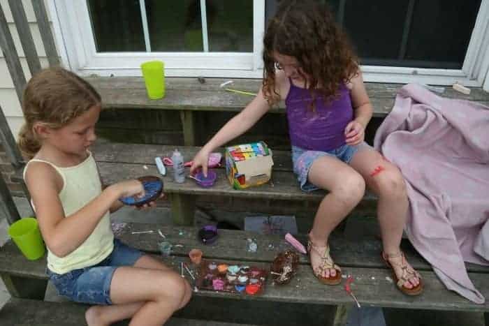 kids covered in sidewalk chalk and pain on the back porch steps 