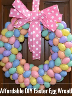 diy wreath made of colorful pastel easter eggs with a pink polka dot bow hanging on a door.