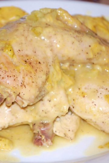 Tender pieces of chicken coated in a creamy yellow curry sauce with chunks of vegetables, served on a white plate.