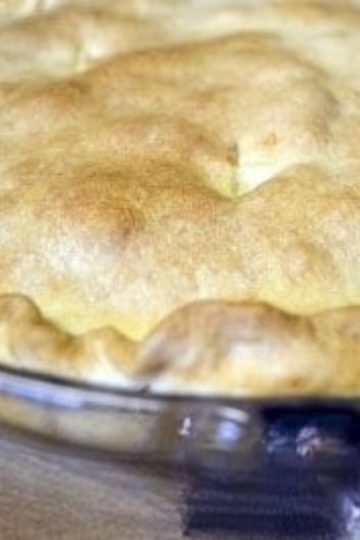 Golden-brown baked pot pie with a flaky, crimped crust in a blue glass pie dish